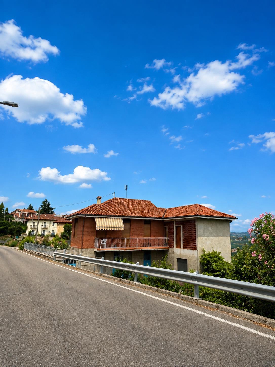 Street view of the house with balcony, awning and vineyard backdrop